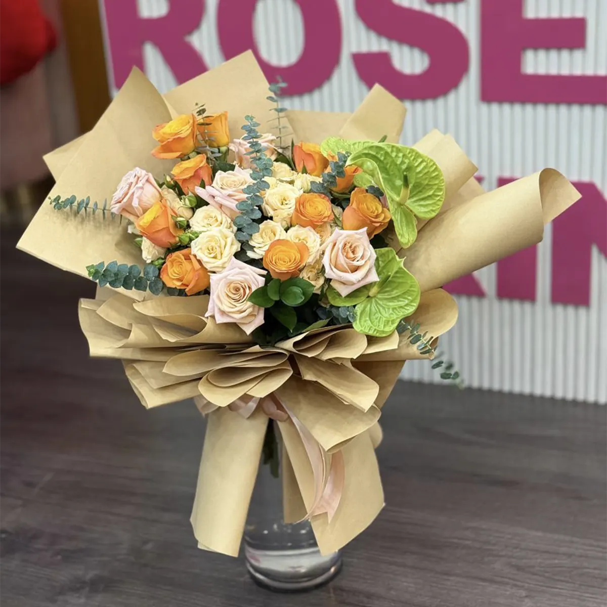 Orange Roses & Anthurium Bouquet of orange and cream roses with green anthurium in kraft paper