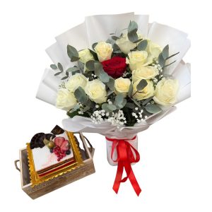 White and red rose bouquet with a cream cake topped with fresh berries in a wooden crate